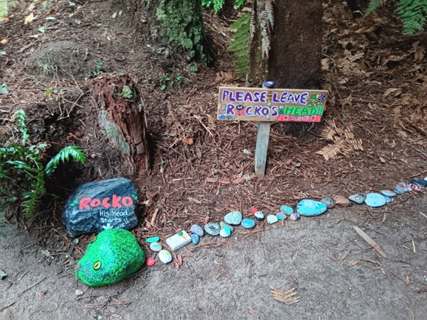 A line of colourful painted rocks on the ground in the forest.